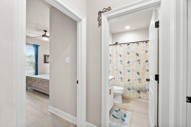 bathroom featuring walk in shower, toilet, vanity, hardwood / wood-style flooring, and ceiling fan