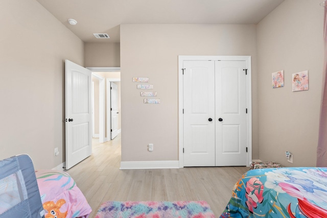 bedroom with light hardwood / wood-style floors and a closet