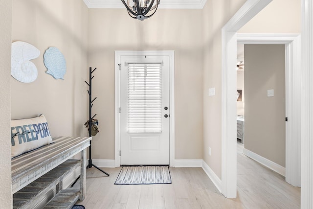 foyer entrance featuring ornamental molding, a chandelier, and light hardwood / wood-style floors