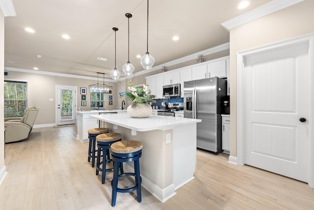 kitchen with a breakfast bar area, white cabinetry, decorative light fixtures, appliances with stainless steel finishes, and a kitchen island