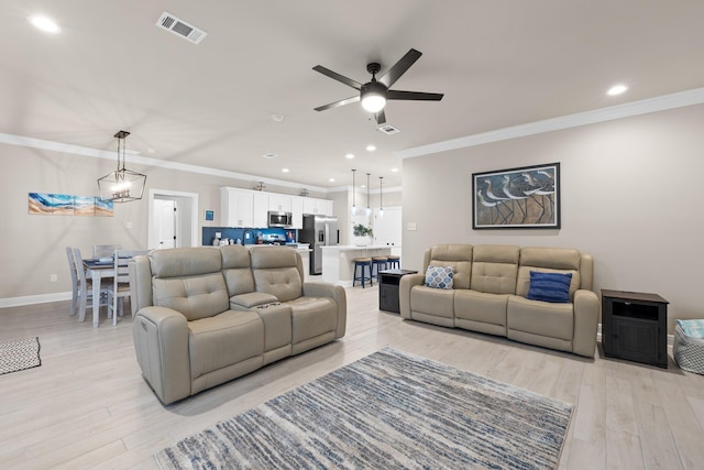 living room featuring ceiling fan with notable chandelier, ornamental molding, and light wood-type flooring