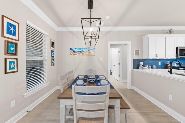 dining space with ornamental molding, a chandelier, and light wood-type flooring