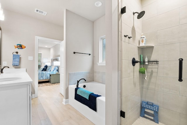 bathroom featuring plus walk in shower, hardwood / wood-style floors, and vanity