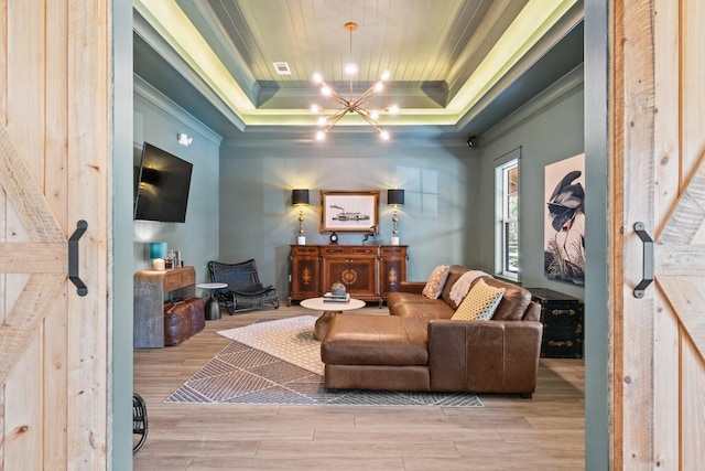 living area featuring crown molding, a chandelier, light wood-type flooring, and a tray ceiling