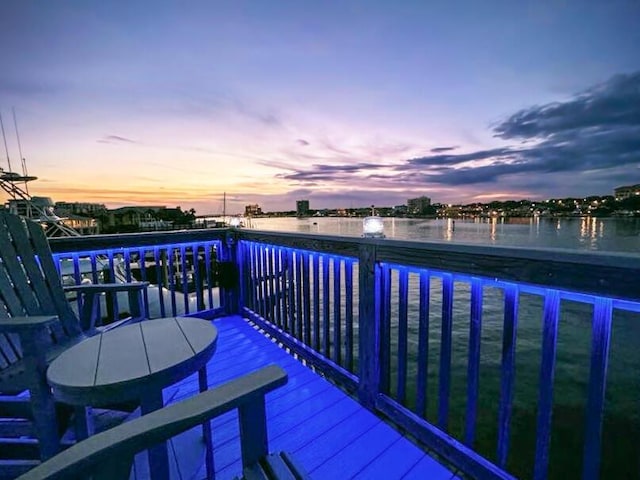 deck at dusk featuring a water view