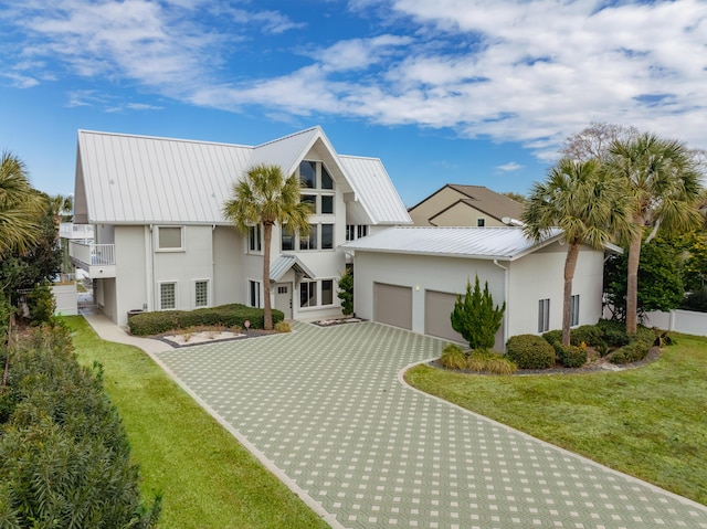 view of front of house featuring a garage, a front lawn, and a balcony