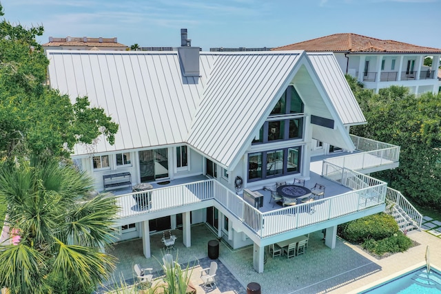 rear view of house with a swimming pool side deck, a patio, and a fire pit