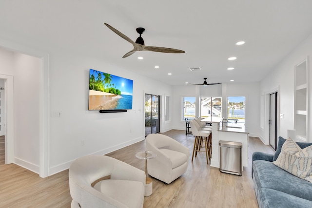 living room with ceiling fan and light hardwood / wood-style flooring