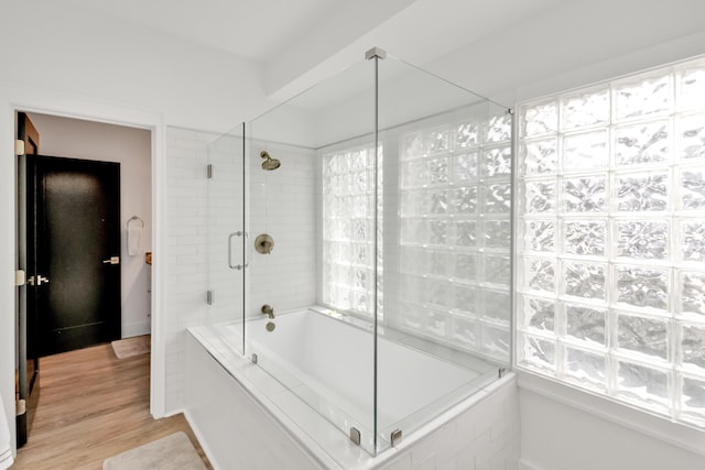 bathroom with hardwood / wood-style flooring and tiled shower / bath