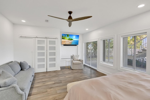 bedroom featuring hardwood / wood-style flooring, ceiling fan, and multiple windows