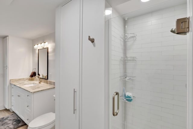 bathroom with hardwood / wood-style floors, vanity, toilet, and a shower with shower door