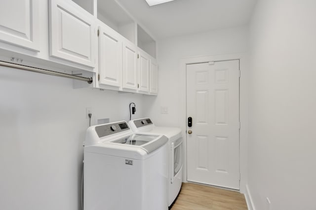 clothes washing area with cabinets, washer and dryer, and light wood-type flooring