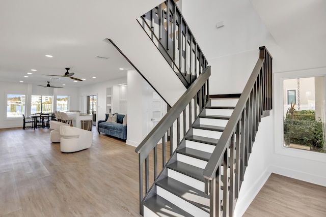 staircase with hardwood / wood-style floors and ceiling fan