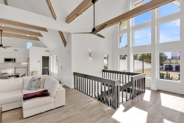 living room with ceiling fan, beam ceiling, high vaulted ceiling, and light wood-type flooring