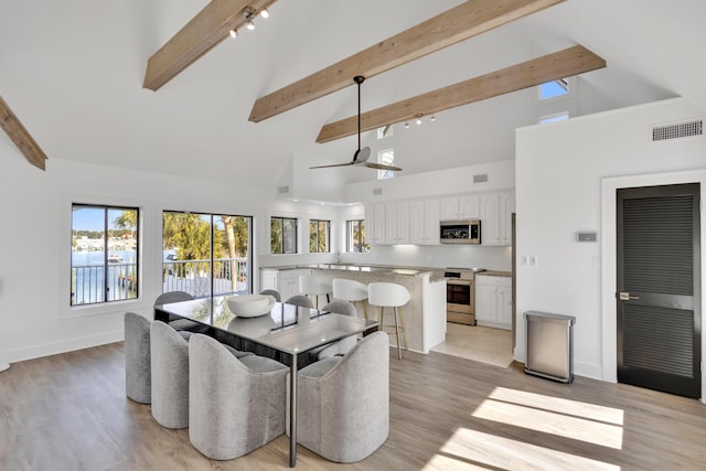 dining area featuring beamed ceiling, high vaulted ceiling, and light hardwood / wood-style floors