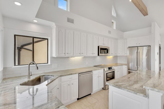 kitchen featuring appliances with stainless steel finishes, white cabinetry, sink, backsplash, and light stone counters