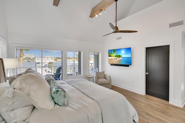 bedroom with multiple windows, high vaulted ceiling, beam ceiling, and light hardwood / wood-style floors