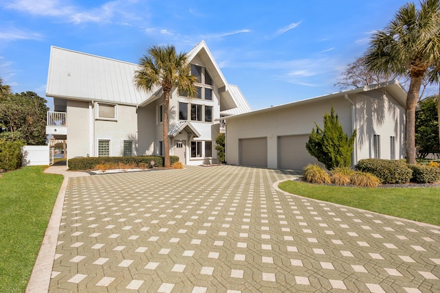 view of front of property featuring a garage, a balcony, and a front yard