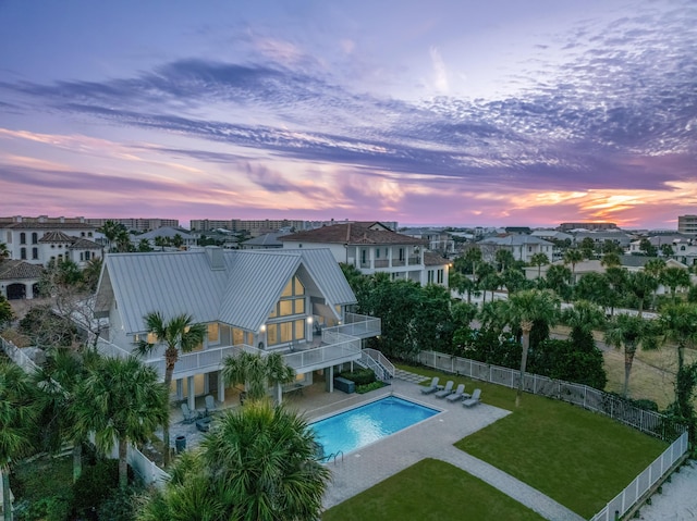 pool at dusk with a yard and a patio area