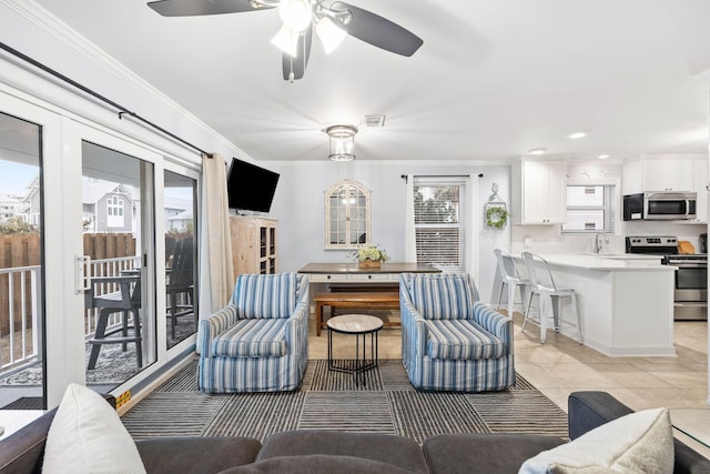 tiled living room featuring crown molding, sink, and a wealth of natural light