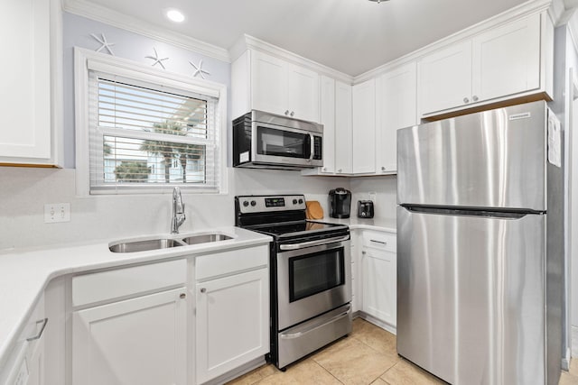 kitchen featuring appliances with stainless steel finishes, sink, white cabinets, ornamental molding, and light tile patterned floors