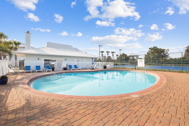 view of swimming pool featuring tennis court