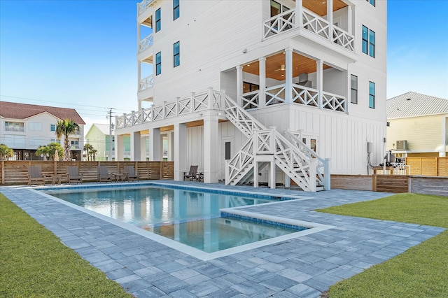 rear view of house with a pool with hot tub, a lawn, and central air condition unit