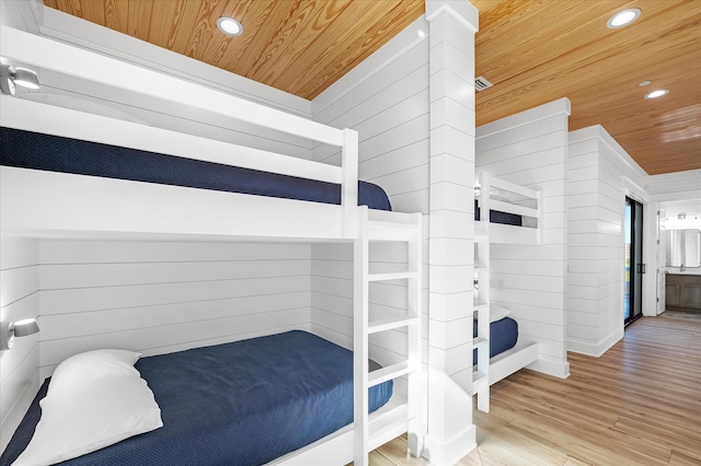 bedroom with wood walls, light wood-type flooring, and wooden ceiling