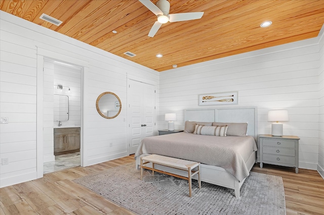 bedroom with connected bathroom, wood walls, wooden ceiling, ceiling fan, and light hardwood / wood-style floors