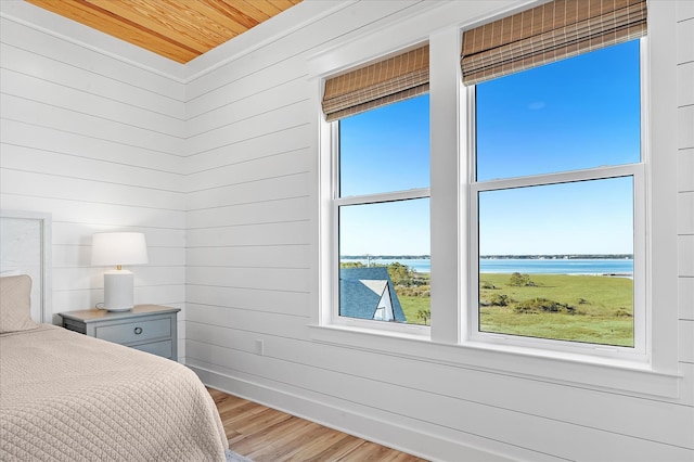 bedroom with a water view, wood ceiling, and hardwood / wood-style flooring