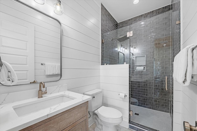 bathroom with wood walls, vanity, an enclosed shower, and toilet