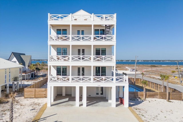 view of front of house with a water view, a carport, a balcony, and central AC