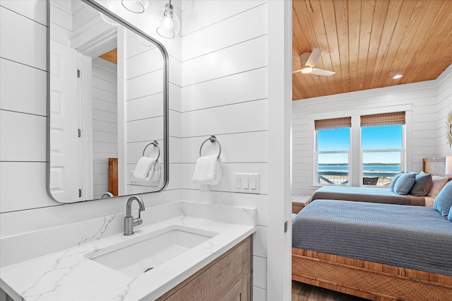 bathroom with ceiling fan, vanity, wooden walls, and wooden ceiling