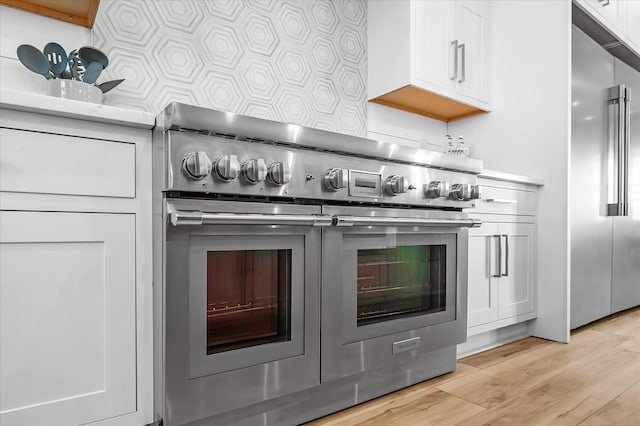 kitchen featuring white cabinets, light hardwood / wood-style floors, and high quality appliances