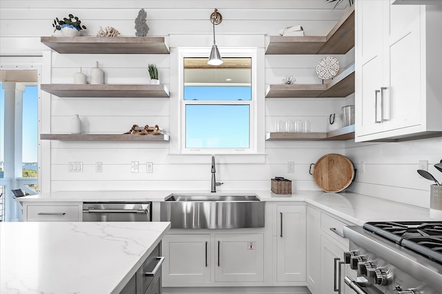 kitchen with white cabinetry, decorative light fixtures, sink, and light stone counters