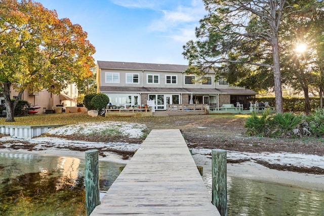 snow covered rear of property with a wooden deck and french doors