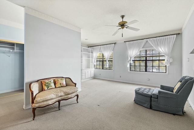 living area with crown molding, light colored carpet, and ceiling fan