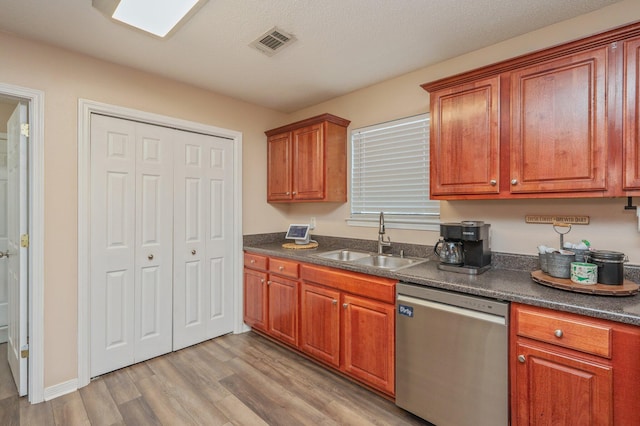 kitchen featuring sink, light hardwood / wood-style flooring, stainless steel dishwasher, and a textured ceiling