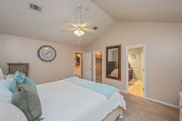 carpeted bedroom featuring connected bathroom, a walk in closet, vaulted ceiling, a closet, and ceiling fan