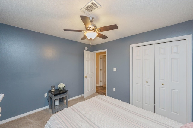 carpeted bedroom featuring a textured ceiling, ceiling fan, and a closet