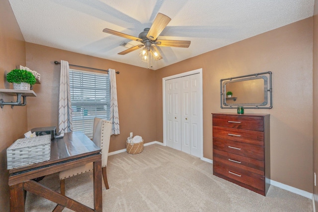 home office featuring light carpet, ceiling fan, and a textured ceiling