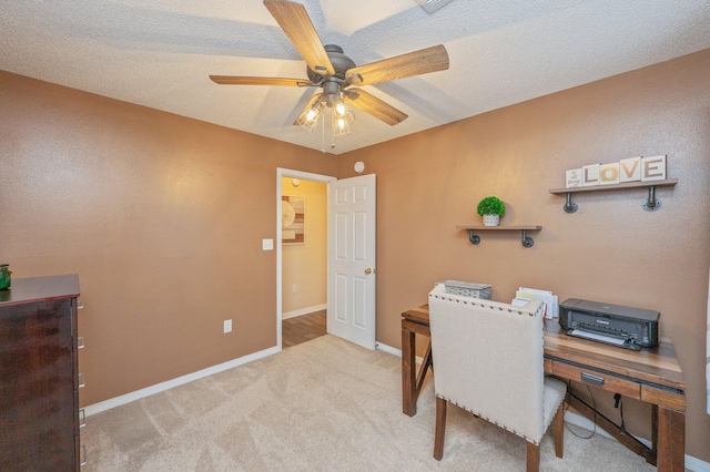 home office featuring light colored carpet, a textured ceiling, and ceiling fan