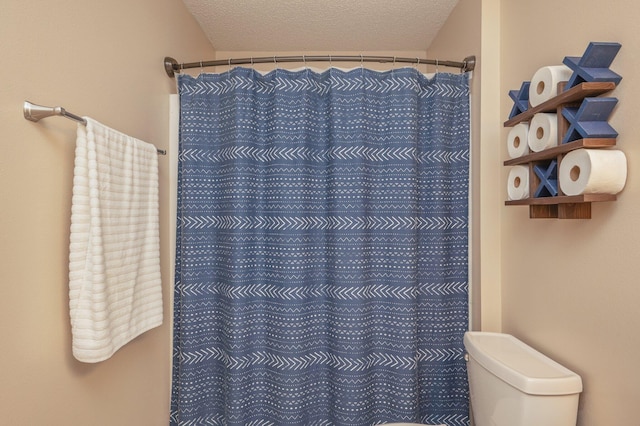 bathroom with a shower with curtain, toilet, and a textured ceiling