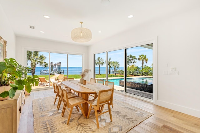 dining space featuring a water view and light hardwood / wood-style flooring