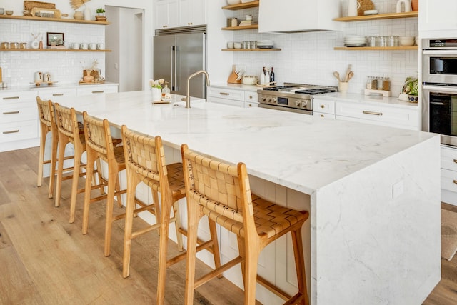 kitchen with light stone counters, a spacious island, appliances with stainless steel finishes, and a kitchen breakfast bar