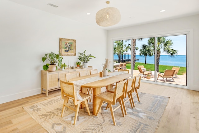 dining space with light hardwood / wood-style flooring and a water view