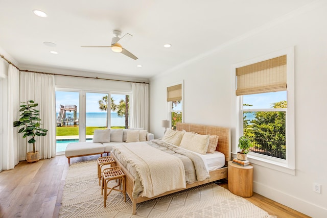 bedroom with multiple windows, a water view, access to exterior, and light wood-type flooring