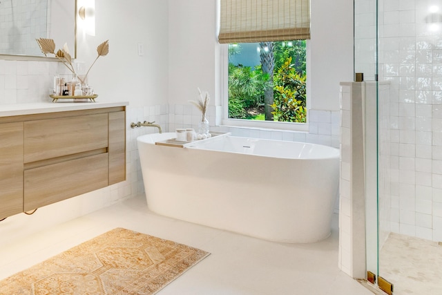 bathroom with tile walls, vanity, and separate shower and tub