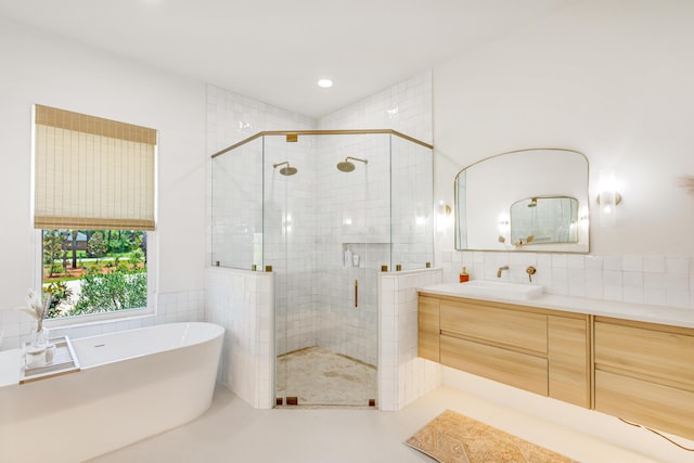 bathroom featuring vanity, independent shower and bath, and tile walls