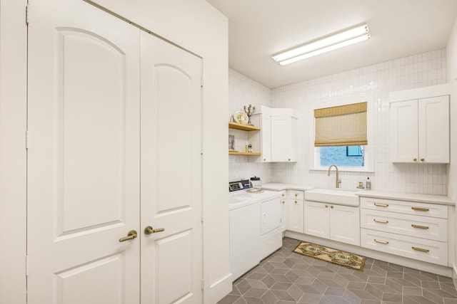 kitchen with sink, dark tile patterned flooring, white cabinets, independent washer and dryer, and backsplash